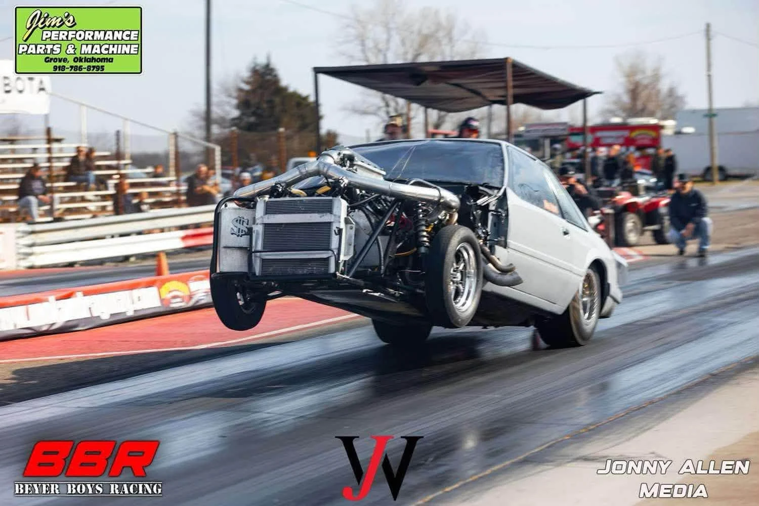 Silver drag racing Mustang launching with its front wheels in the air